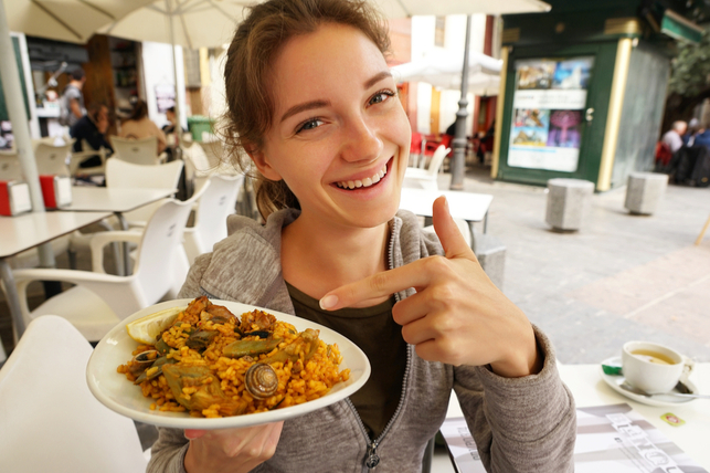 photo of woman pointing at paella