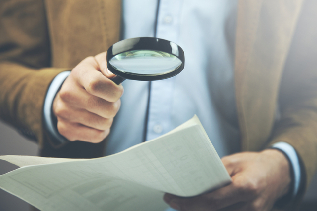 man reading document with magnifying glass