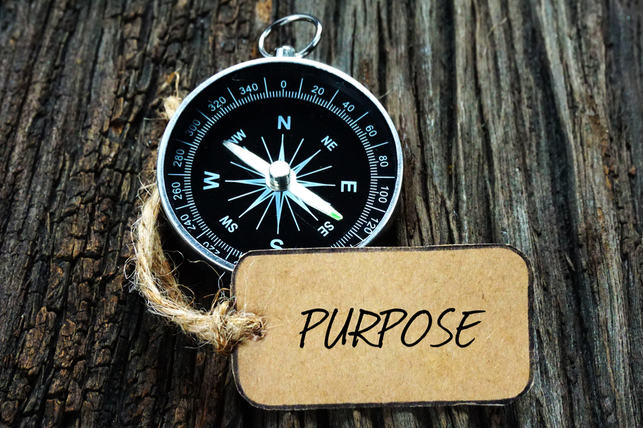 a compass on a wooden table with a tag that says purpose