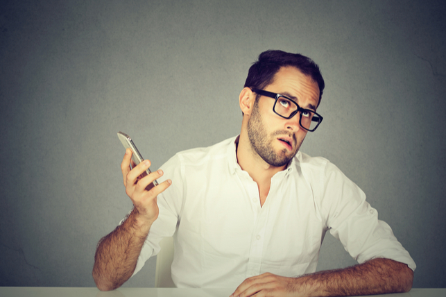 a man bored with a phone call holding the phone away from his head