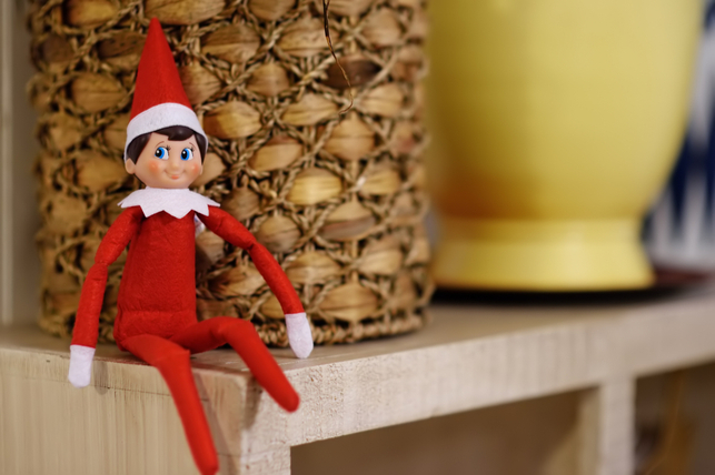 An elf sitting on a shelf.